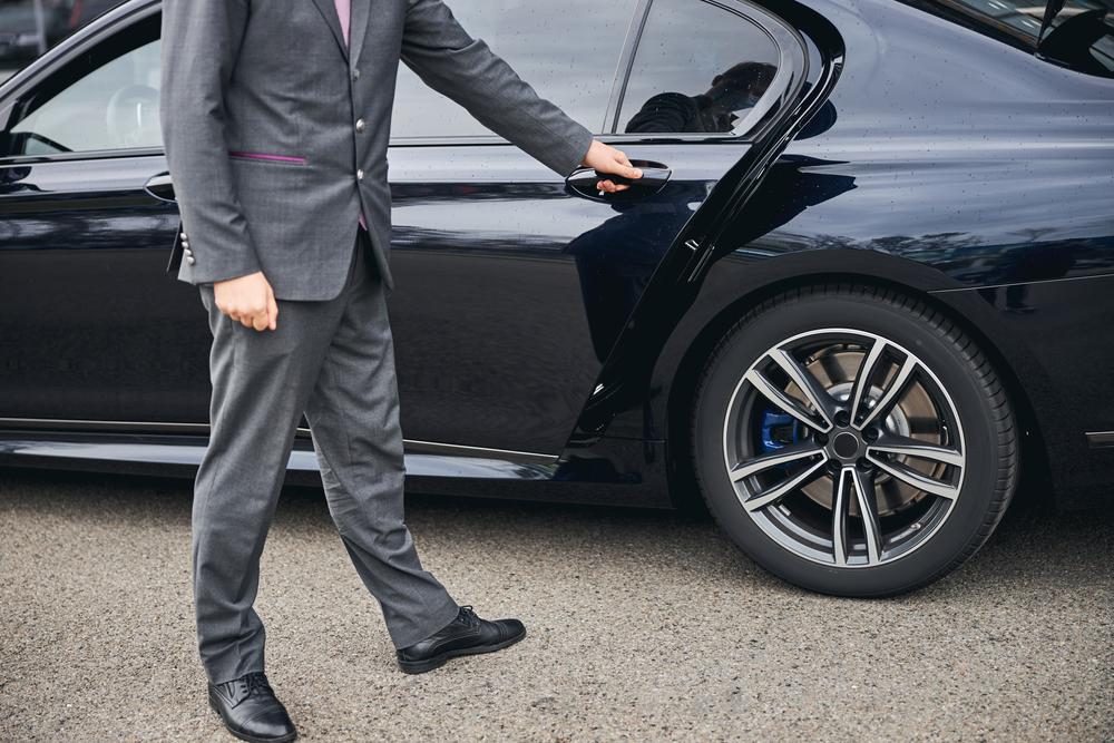 G4 Cars driver opening the door of a 6 seater taxi for a Heathrow Airport transfer